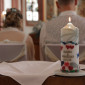 Eine Kerze steht im Rücken eines Hochzeitpaares.
