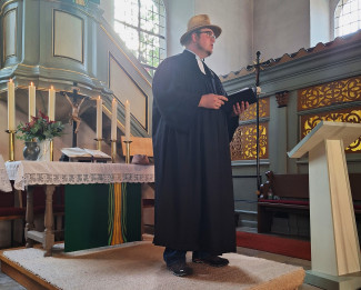 Pfarrer mit Strohhut in Kirche vor Altar