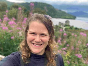 Chantal Fiedler vor einem Blumenfeld im Hintergrund eine Burg